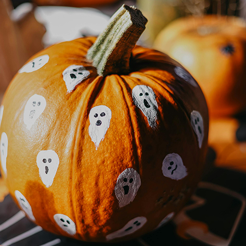 A real pumpkin covered in ghosts using black and w